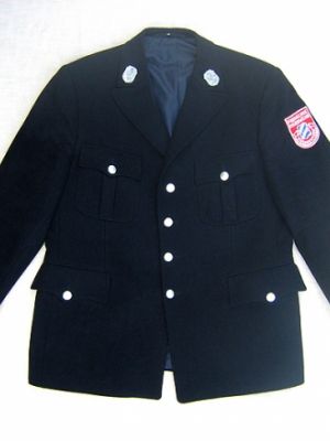 Wollstoff, dunkelblau, mit 90% Schurwolle und 10% Viskose, Hersteller Ziegler. Herstellungsjahr nach 1950. Größe 26, deshalb ausgemustert. (Zum Vergleich: die jetzigen Uniformjacken bestehen aus 55% Polyester und 45 % Schurwolle.)