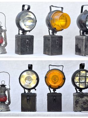 Links: Petroleumsignallampe mit rotem Glas, Original-Nier-Feuerhand, Super 176 Spec. SABY W.Germany, wahrscheinlich ab/Mitte 1950. Daneben: Batterie-Handscheinwerfer, Hersteller jeweils Eisenmann. Links: Lampe mit Klarglas, Typ KB130. Mitte: Lampe mit gelbem Signalvorsatz, Typ K130. Rechts: Lampe mit Schutzgitter und Schlüssel zum Öffnen des Batteriefachs, ohne Typangabe.